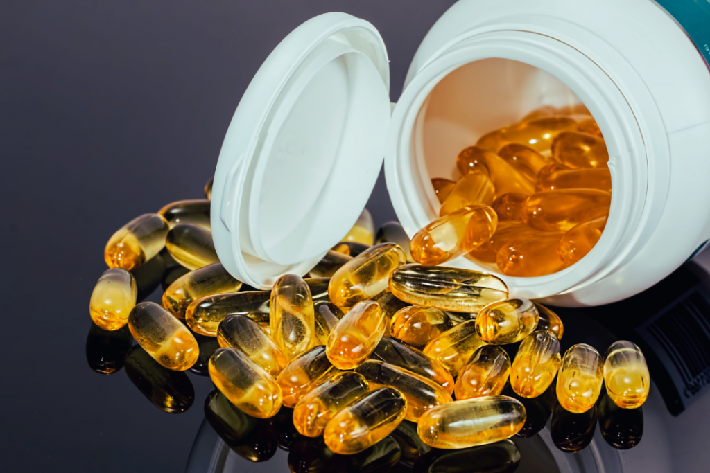 a group of yellow pills spilling out of a white container showing omega-3s supplement for energy and focus